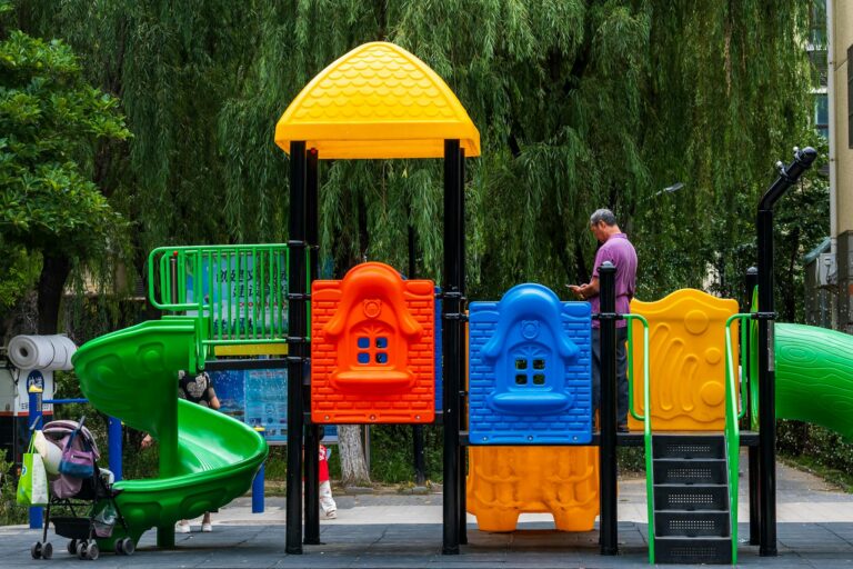 Bright playground with slides and people in a city park during summer.