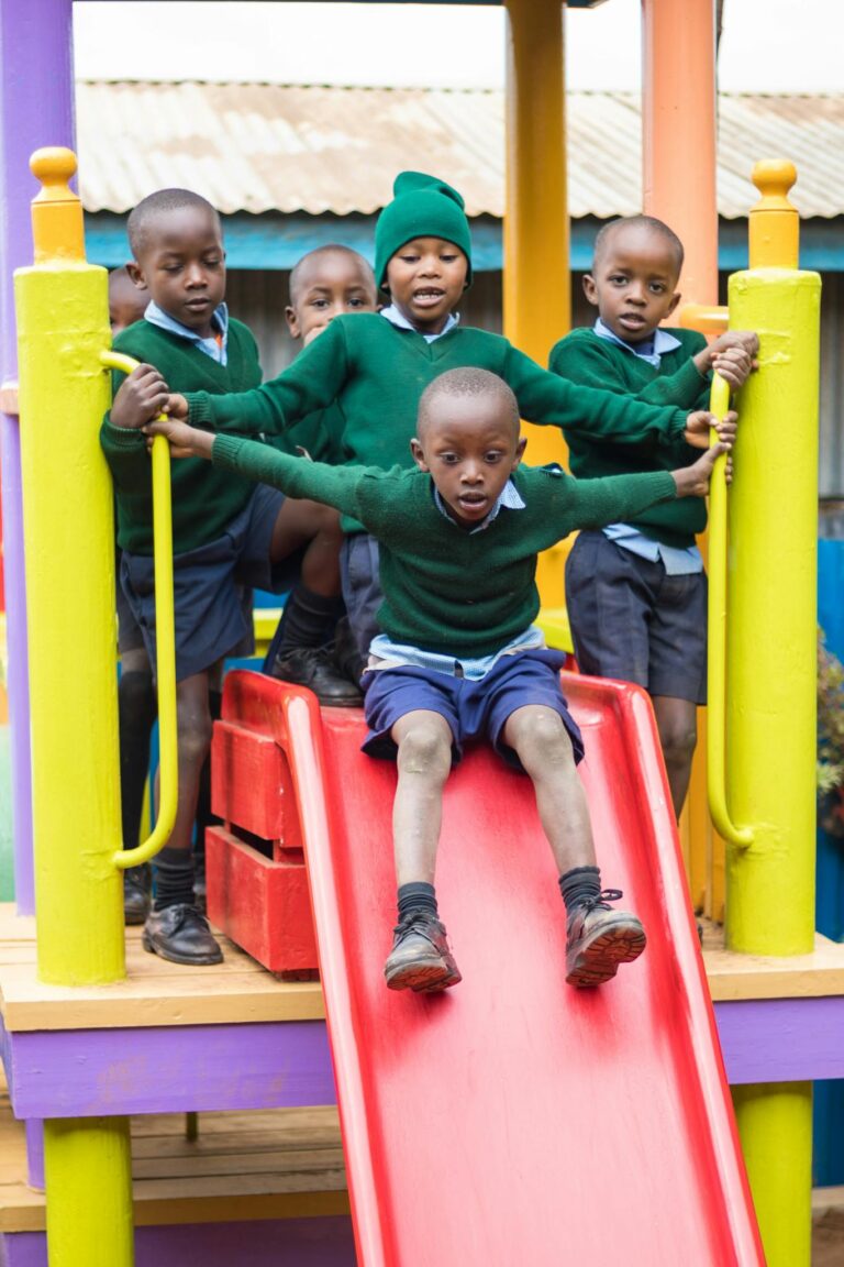 Five schoolchildren enjoy a playground slide in their uniforms, capturing a joyful outdoor moment.