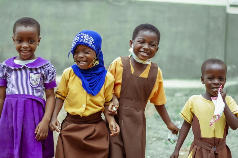 Happy children in school uniforms smiling and enjoying break time outside in Accra, Ghana.