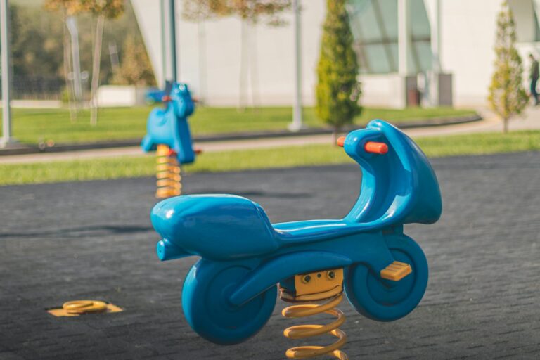 Vibrant blue spring rockers on a sunny day, perfect for children's outdoor fun.